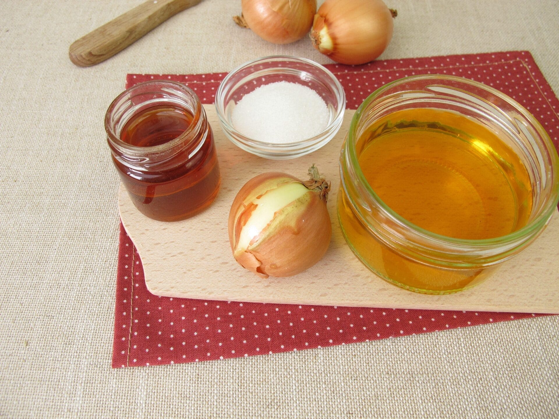onion juice in a small container and onion bulbs placed on a table