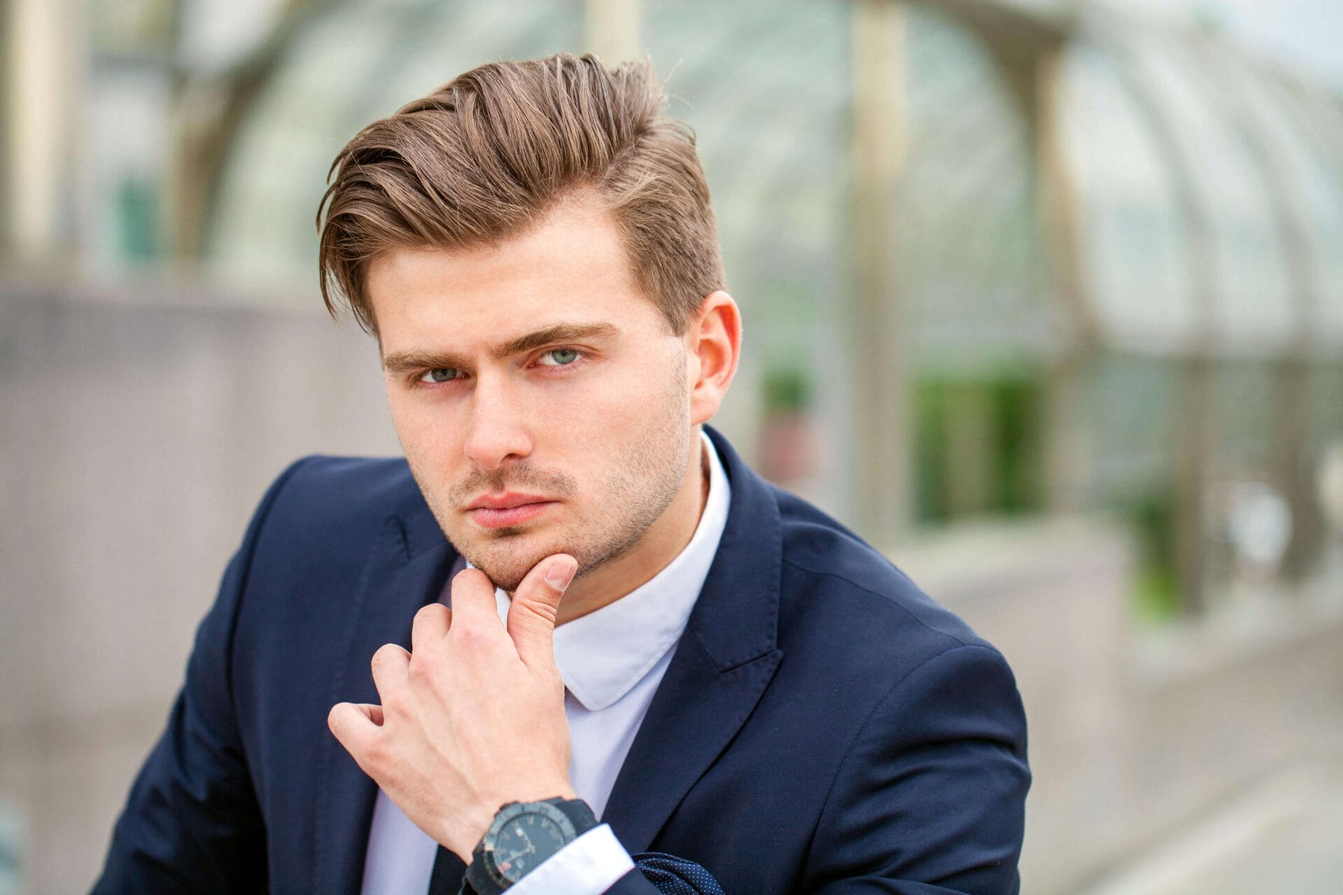 Portrait of a cheerful businessman in black suit, summer street outdoors