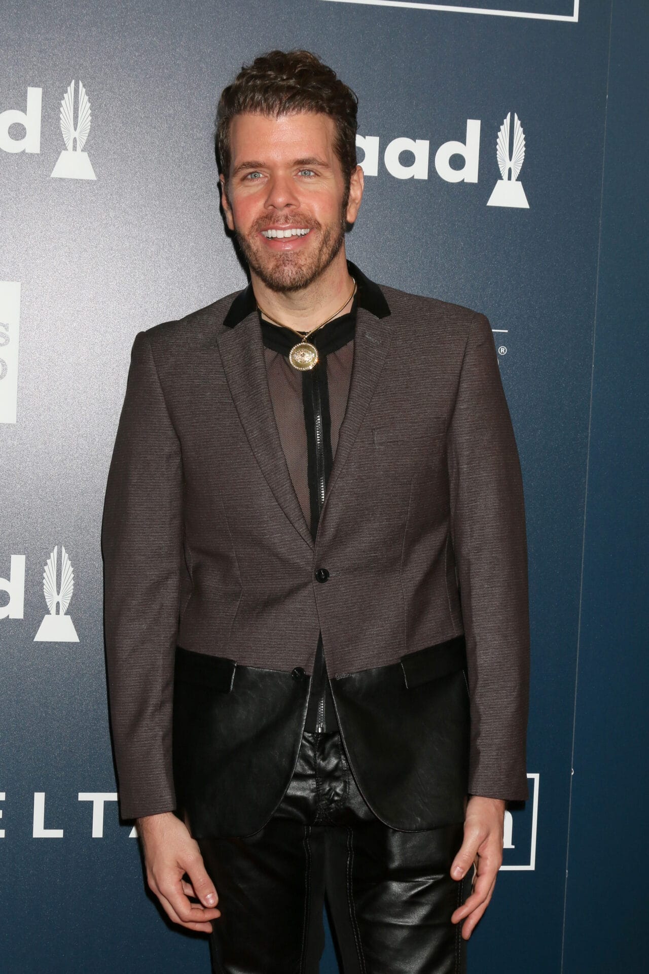 perez hilton with full hairline wearing black pants and brown jacket at an event in Florida